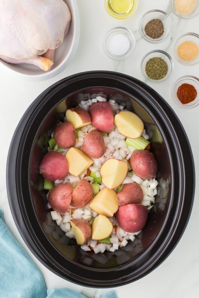 overhead shot of red skin potatoes and onions in a slow cooker.