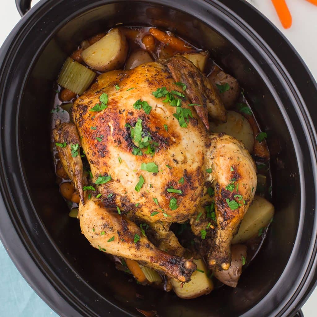 overhead shot of a whole chicken in a black crockpot.