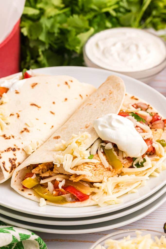 plated chicken fajita topped with cheese and sour cream.