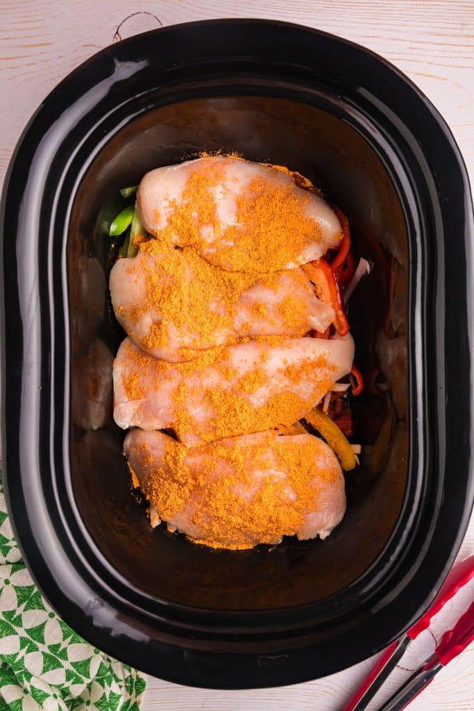 overhead shot of seasoned chicken in a slow cooker.