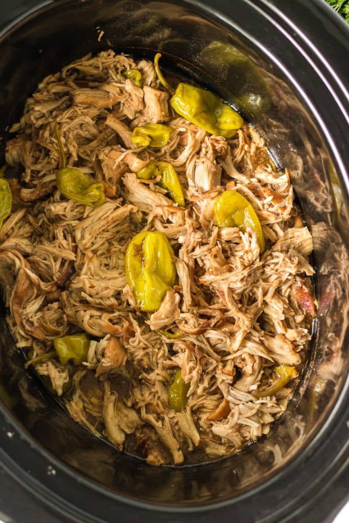 shredded chicken in a slow cooker with pepperoncinis.