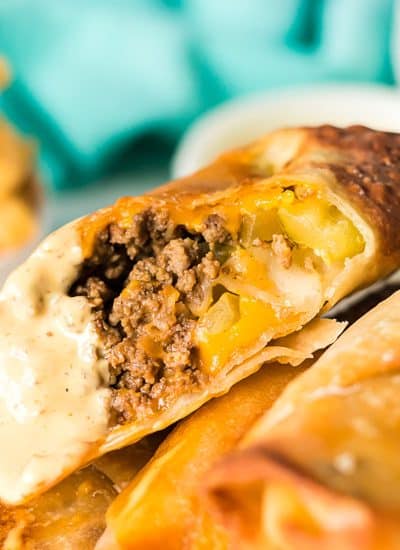 cheeseburger egg roll sliced in half dipped in special sauce.