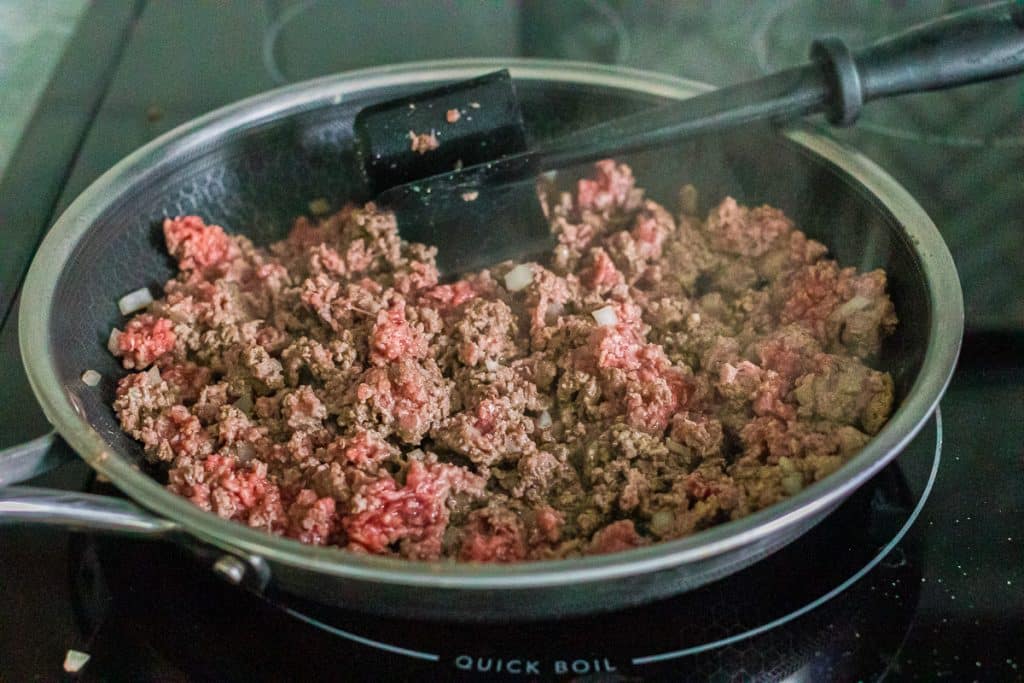 ground beef in a skillet with a meat chopper.