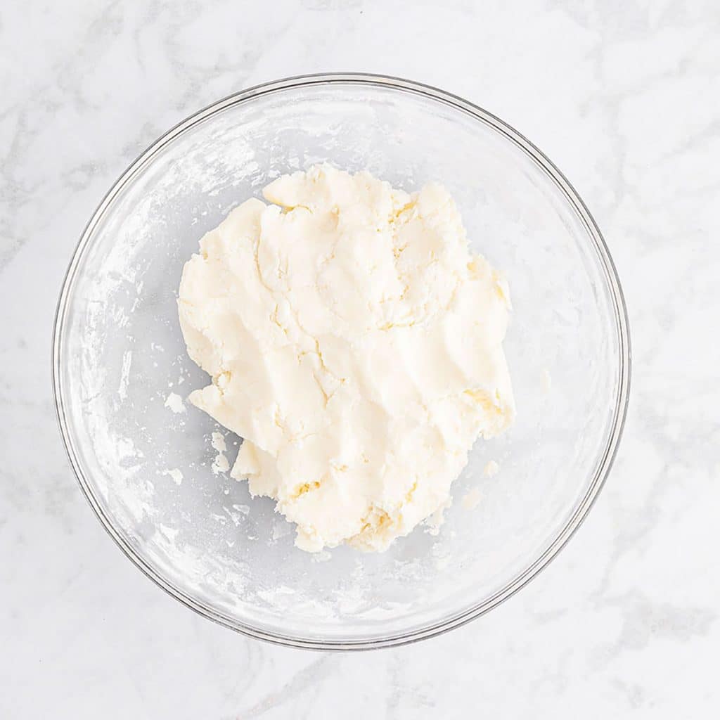 overhead shot of white sugar dough in a mixing bowl.