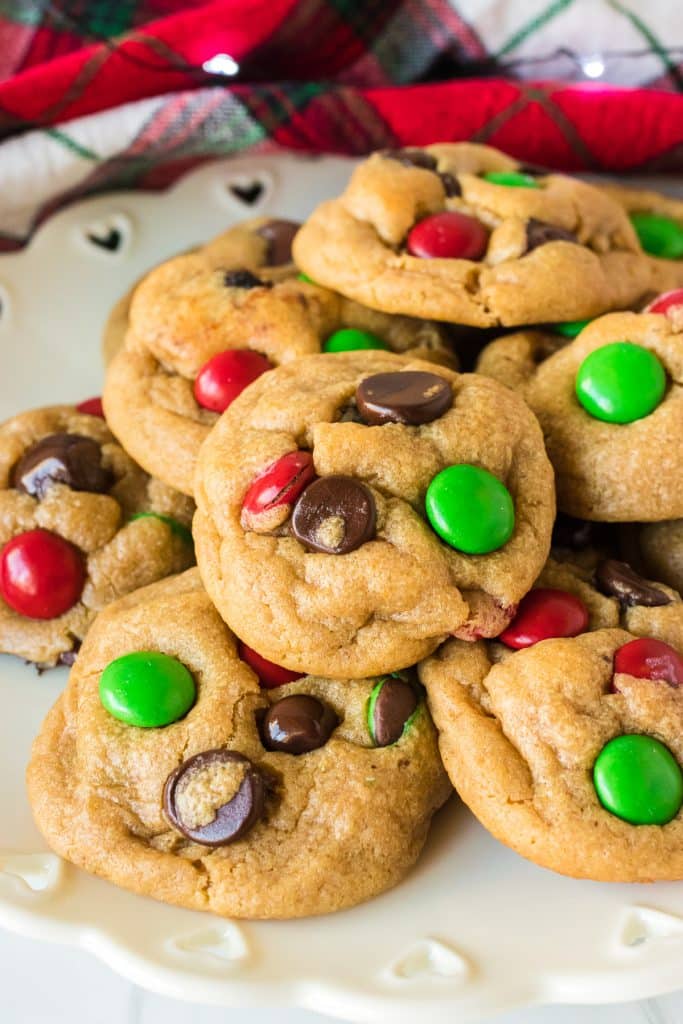 pile of M&M christmas cookies on a white plate.