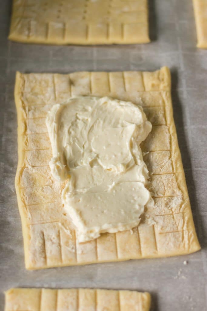 closeup of cream cheese filling spread onto a puff pastry rectangle.
