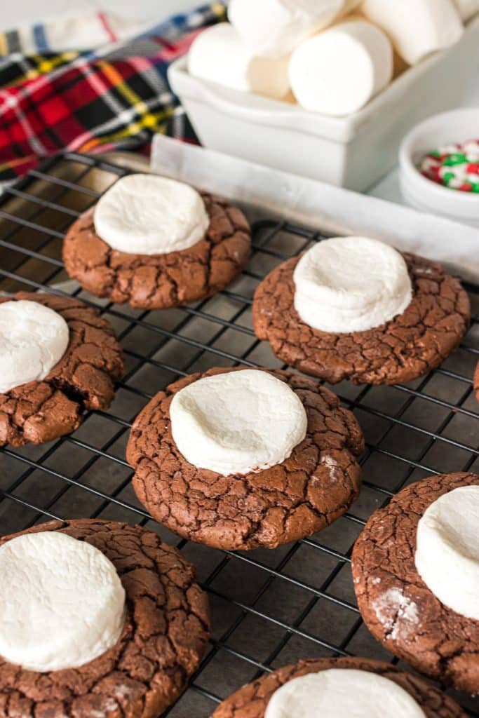chocolate cookies topped with half a marshmallow on a cooling rack.