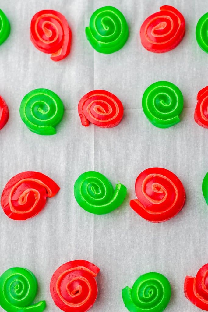red & green jello pinwheels on parchment paper.