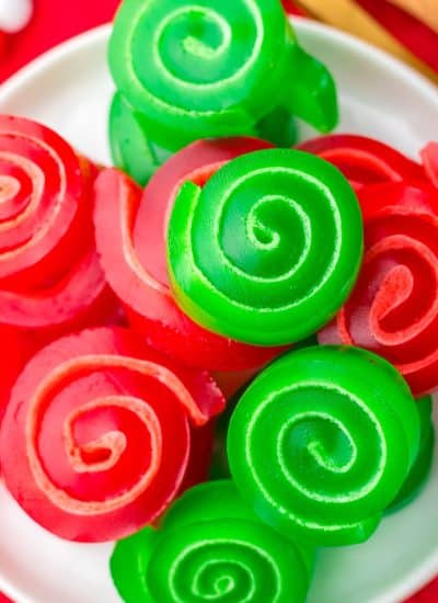 overhead shot of christmas jello roll ups on a white plate.