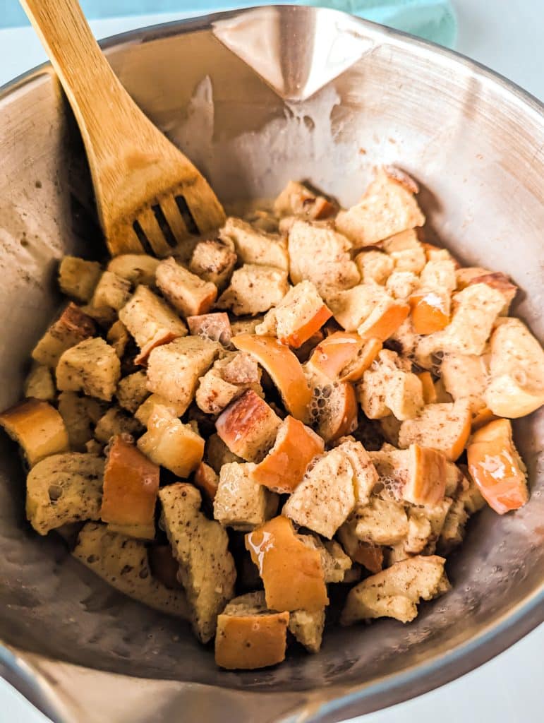 cubed bread in a mixing bowl with a wooden spoon.