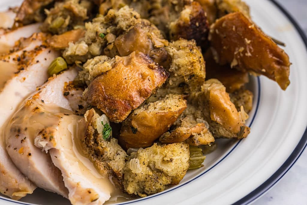 closeup of stuffing, turkey, and gravy on a plate.