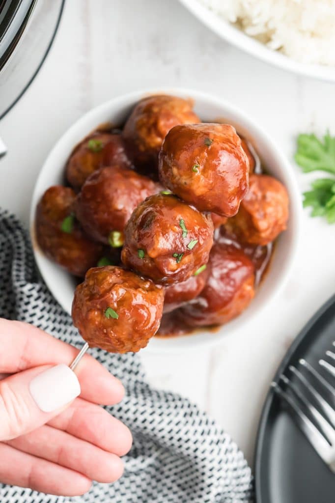 hand holding meatballs on a skewer.