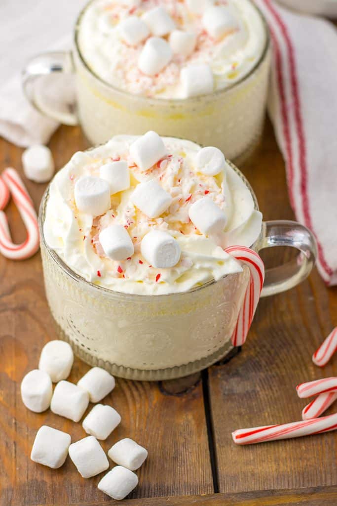 two glass mugs of white hot chocolate with candy canes.