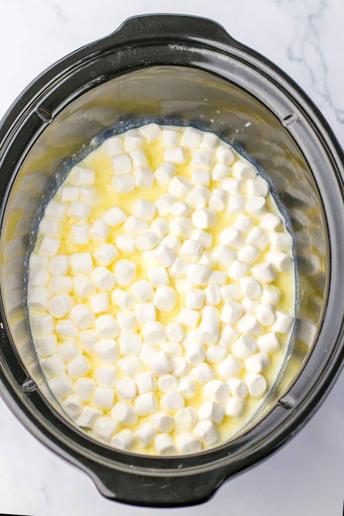 overhead shot of white hot chocolate with marshmallows in a black crockpot.
