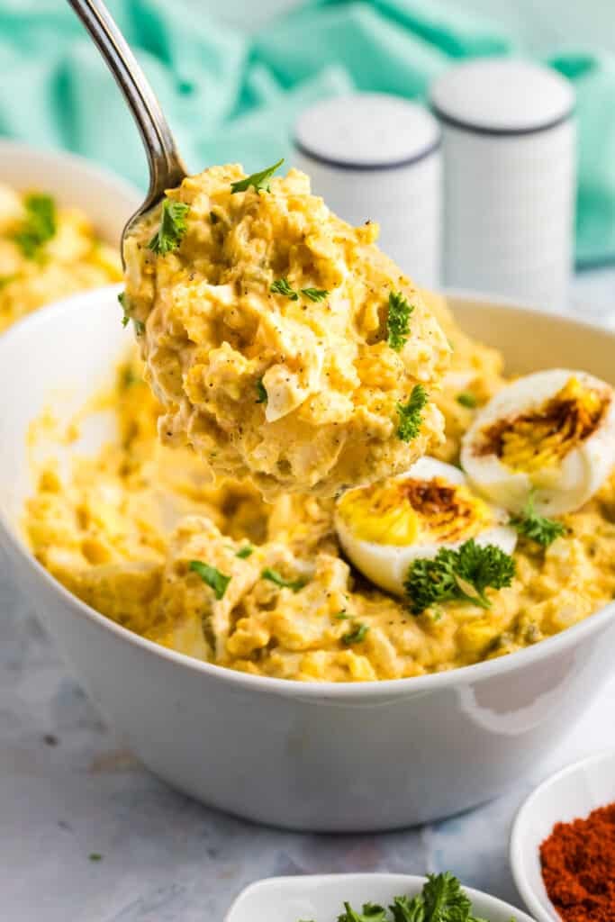 spoon of deviled egg potato salad being lifted from a bowl.