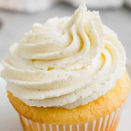 closeup of vanilla buttercream piped onto a yellow cupcake.