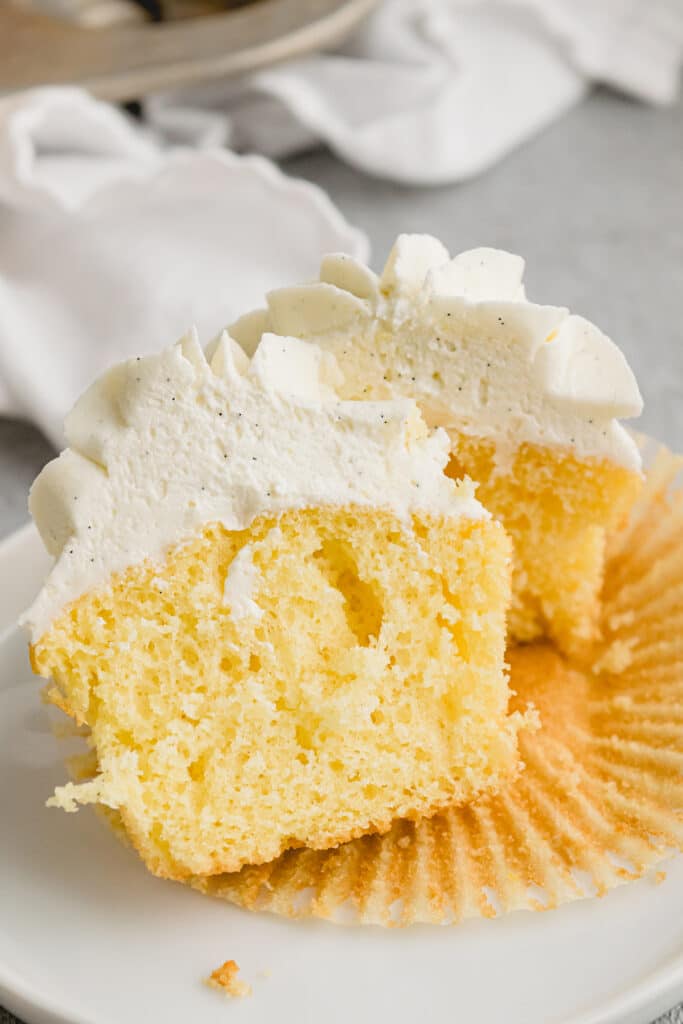 yellow cupcake sliced in half with vanilla buttercream.