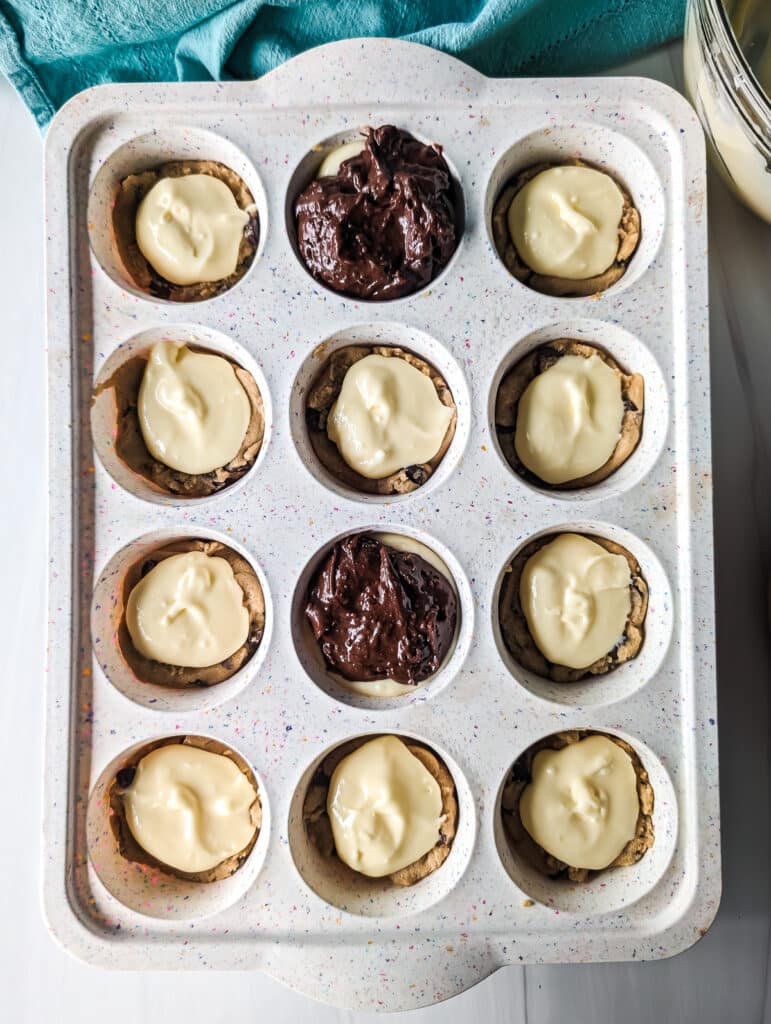overhead shot of brownie batter and cheesecake filling in a muffin pan.