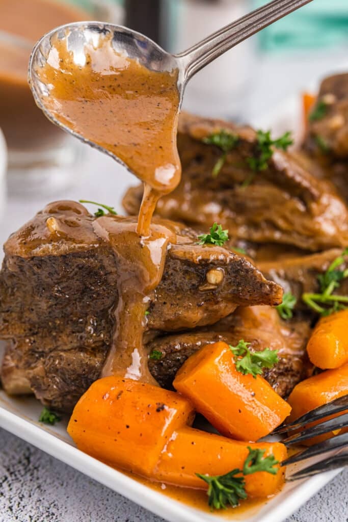 brown gravy drizzling onto short ribs and carrots.