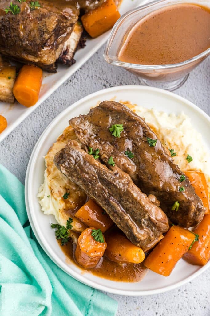 short ribs on a plate with mashed potatoes and carrots.