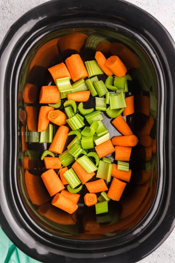 chopped carrots & celery in a black crockpot.