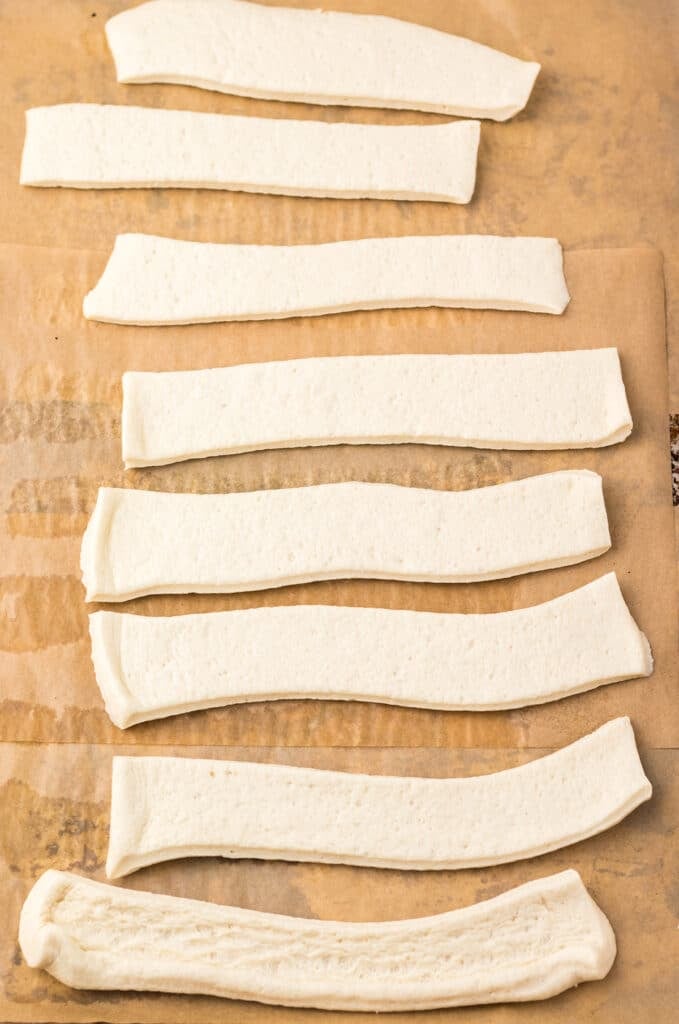 Strips of uncooked bread dough on parchment paper.