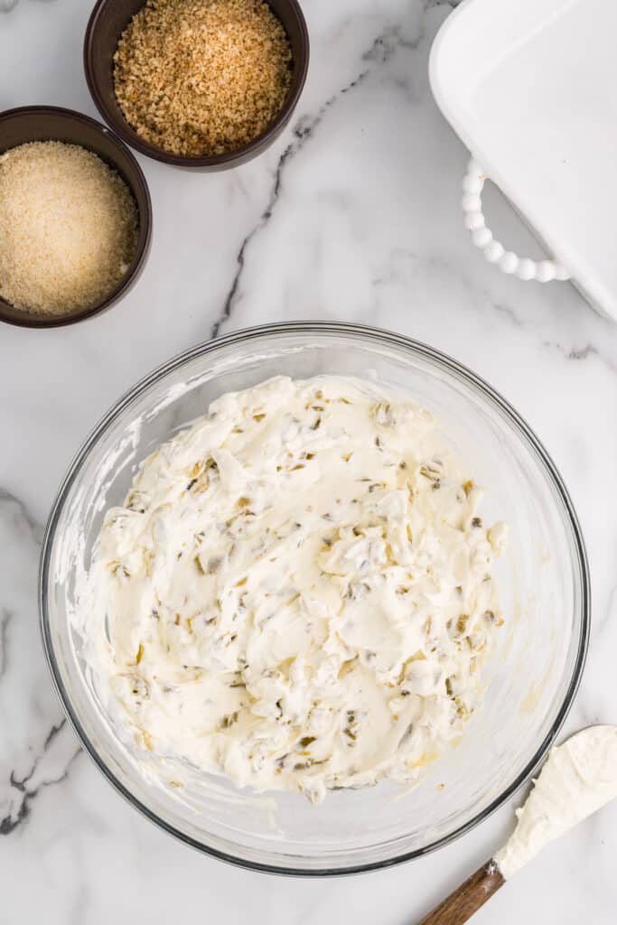 Creamy jalapeño dip mixture in a glass mixing bowl.