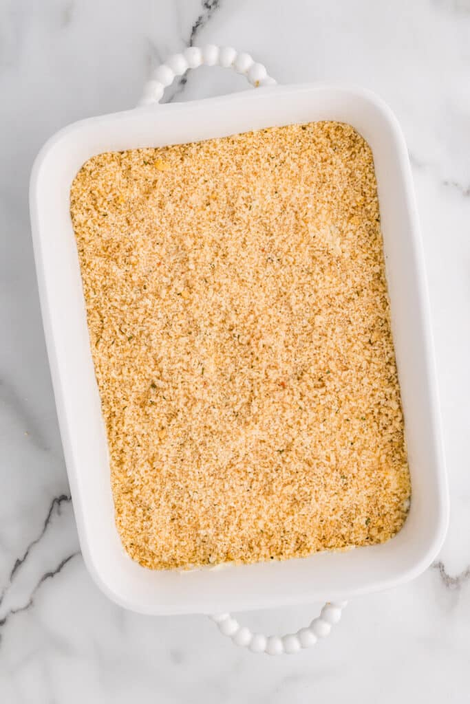 Unbaked jalapeño popper dip topped with breadcrumbs in a white baking dish.