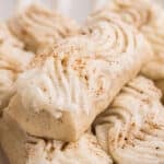 Rectangular cookies topped with piped white frosting and sprinkled with nutmeg.