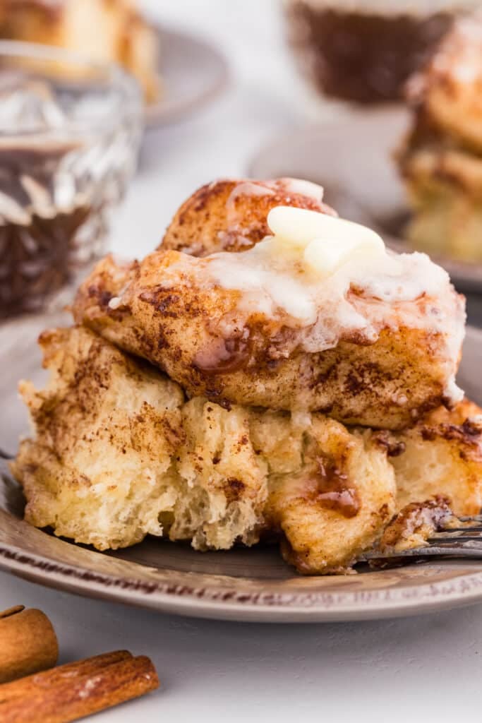 Cinnamon roll piece topped with icing on a plate.