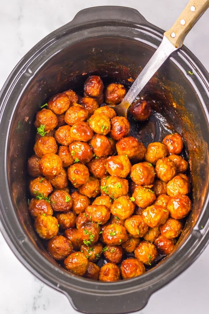 Overhead view of sauced meatballs inside a black slow cooker.