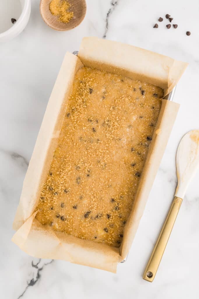 Banana bread with chocolate chips in a parchment-lined loaf pan.