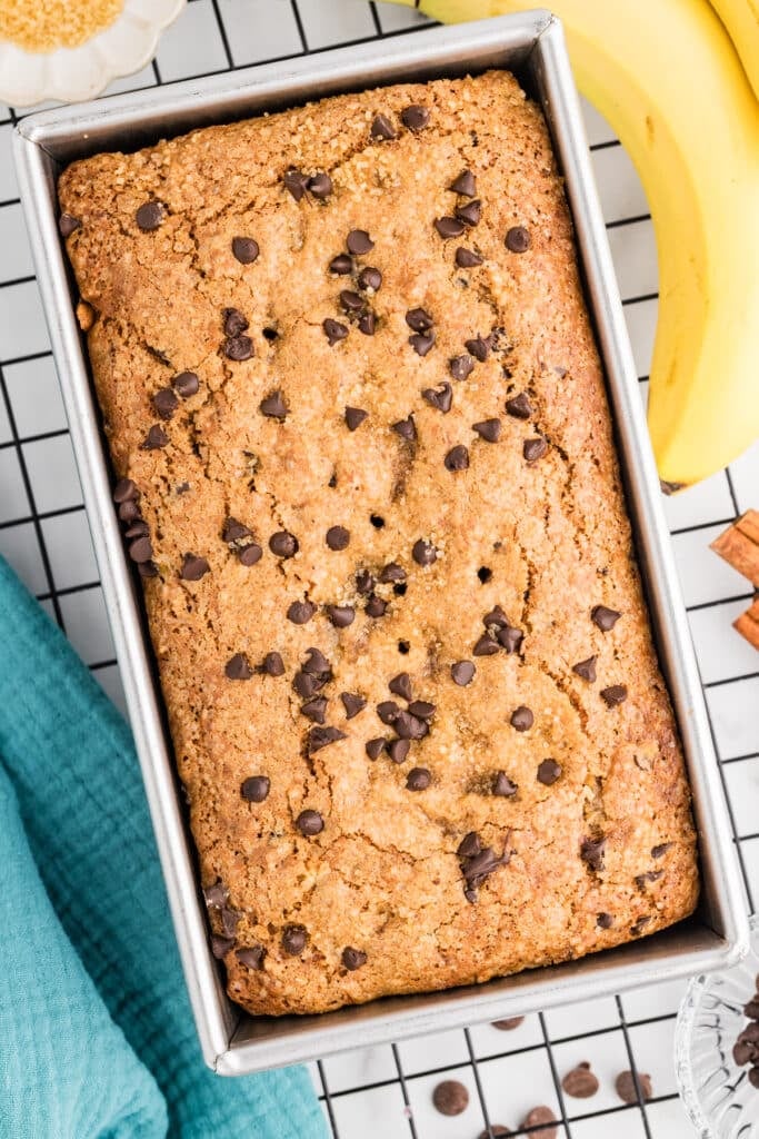 Chocolate chip banana bread baked in a loaf pan with a golden sugar crust and chocolate chips on top.