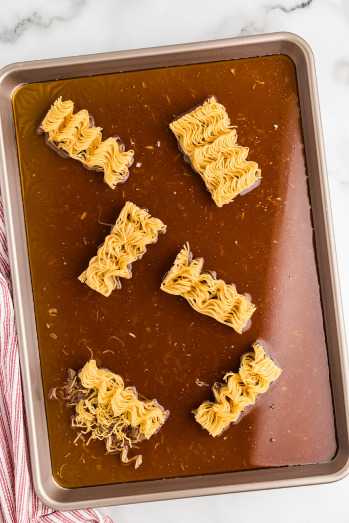 Sheet pan with ramen noodle blocks in brown sauce.