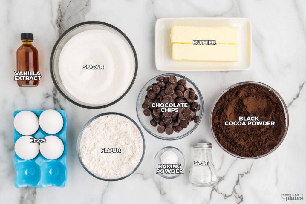 Ingredients for dark cocoa brownies including black cocoa powder, chocolate chips, butter, sugar, eggs, flour, and vanilla extract.