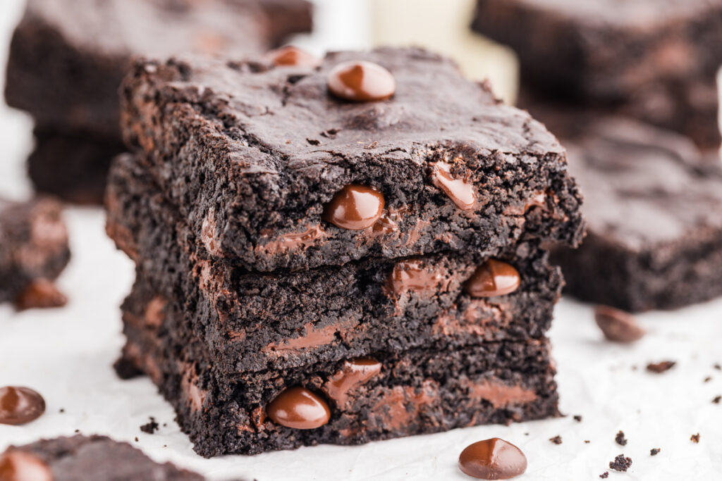 Stack of dark chocolate brownies with melted chocolate chips and a fudgy texture.