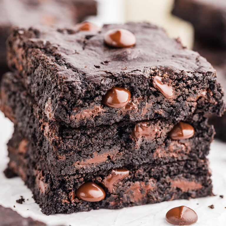 Stack of dark chocolate brownies with melted chocolate chips inside and on top.