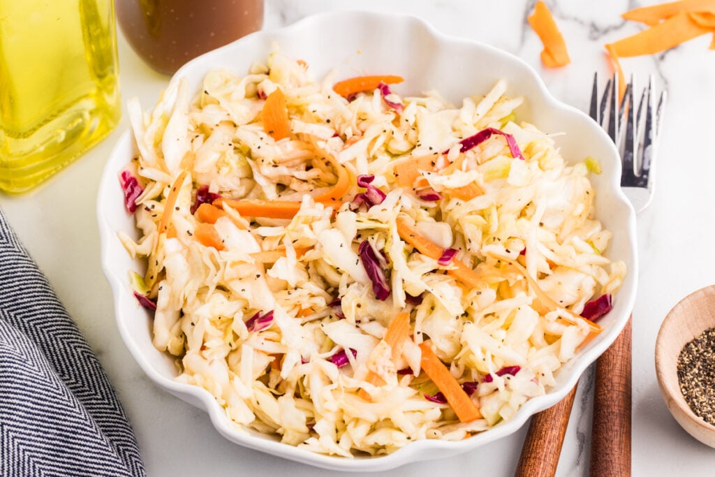 Vinegar coleslaw with cabbage, carrots, and purple cabbage in a white serving bowl.